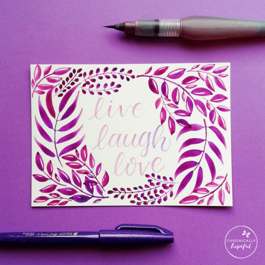 Leafy watercolour composition in purple on white card, the words Live, Laugh, Love lettered in the middle.