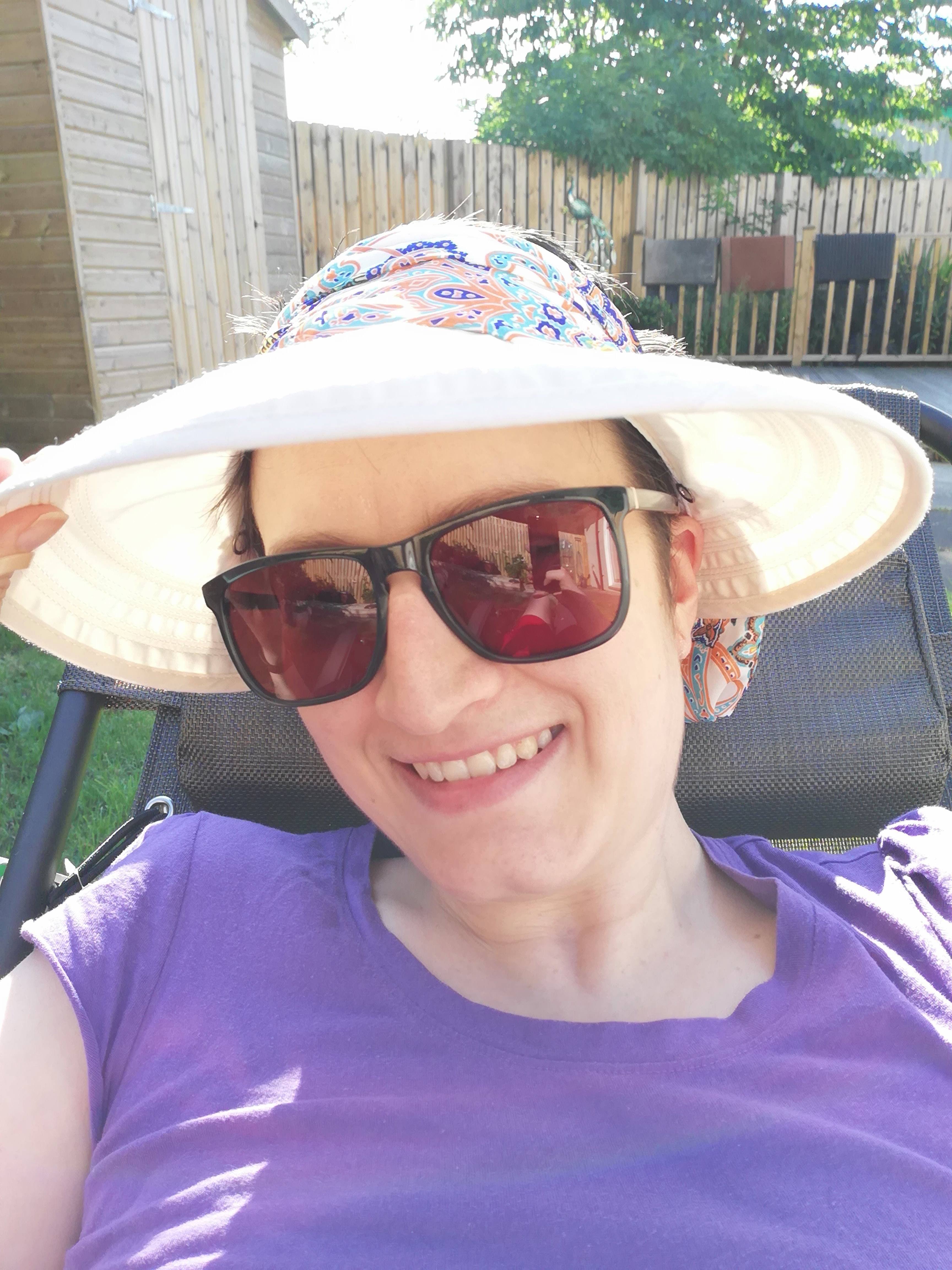 Char lying on garden recliner. She's wearing a sun hat and sunglasses