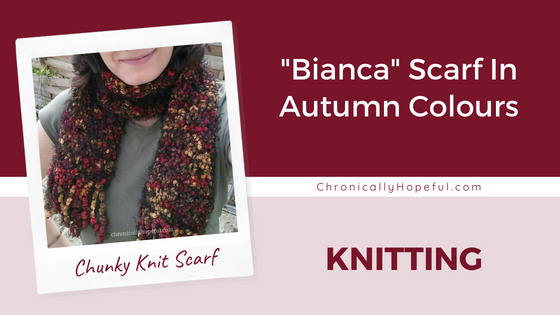 Char wearing a knitted scarf she made. It's black with autumn colour speckles. Title Reads: Bianca Scarf In Autumn Colours