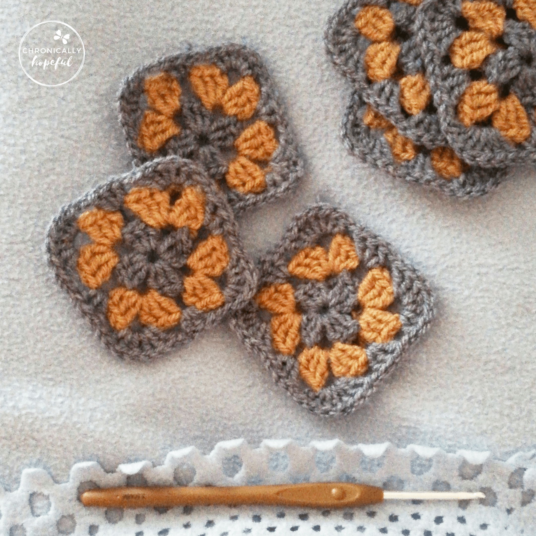 Crocheted granny squares in blue and brown, lying on a blanket. Brown crochet hook to the bottom of the picture.