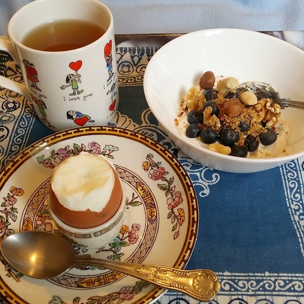 A boiled egg, coconut yogurt with nuts and seeds and a cup of tea.