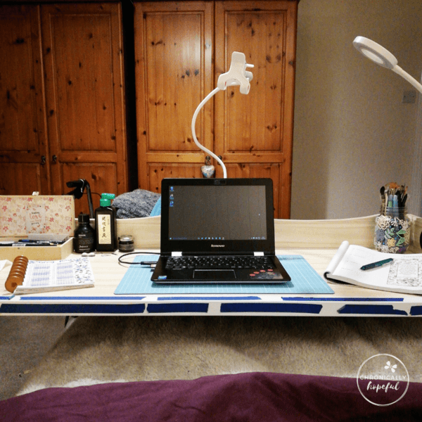 My over the bed desk with my laptop and journals