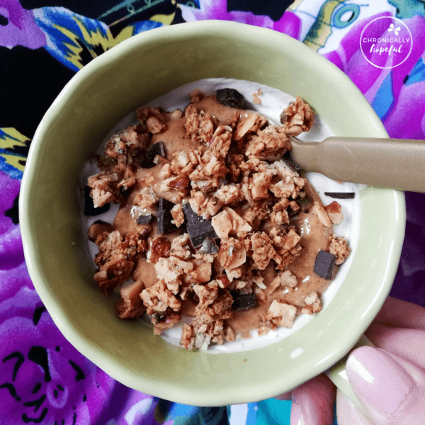 Char holding a cup of yogurt with nut butter and keto granola on top