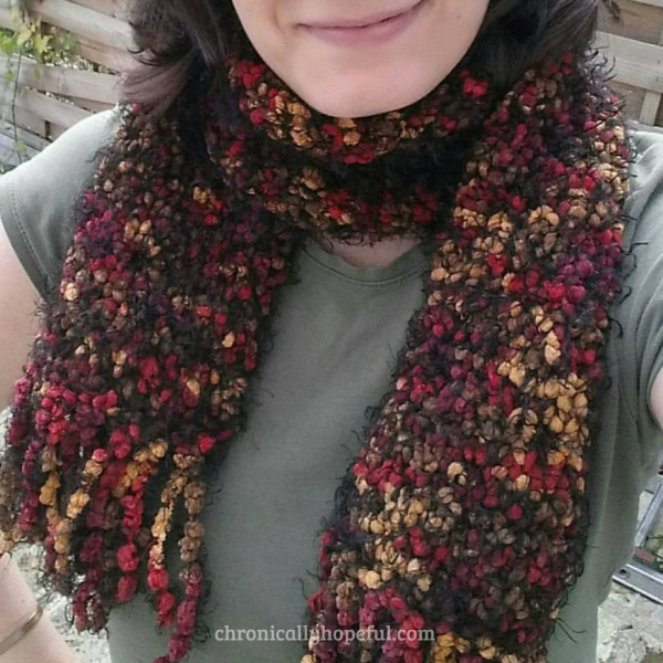 Char wearing a knitted scarf she made. It's black with autumn colour speckles